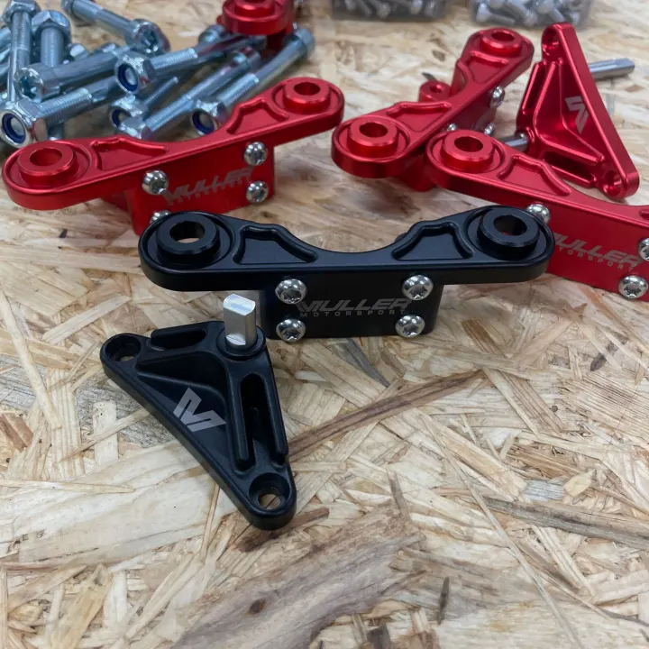Black and red Muller Motorsport steering damper brackets on a workbench
